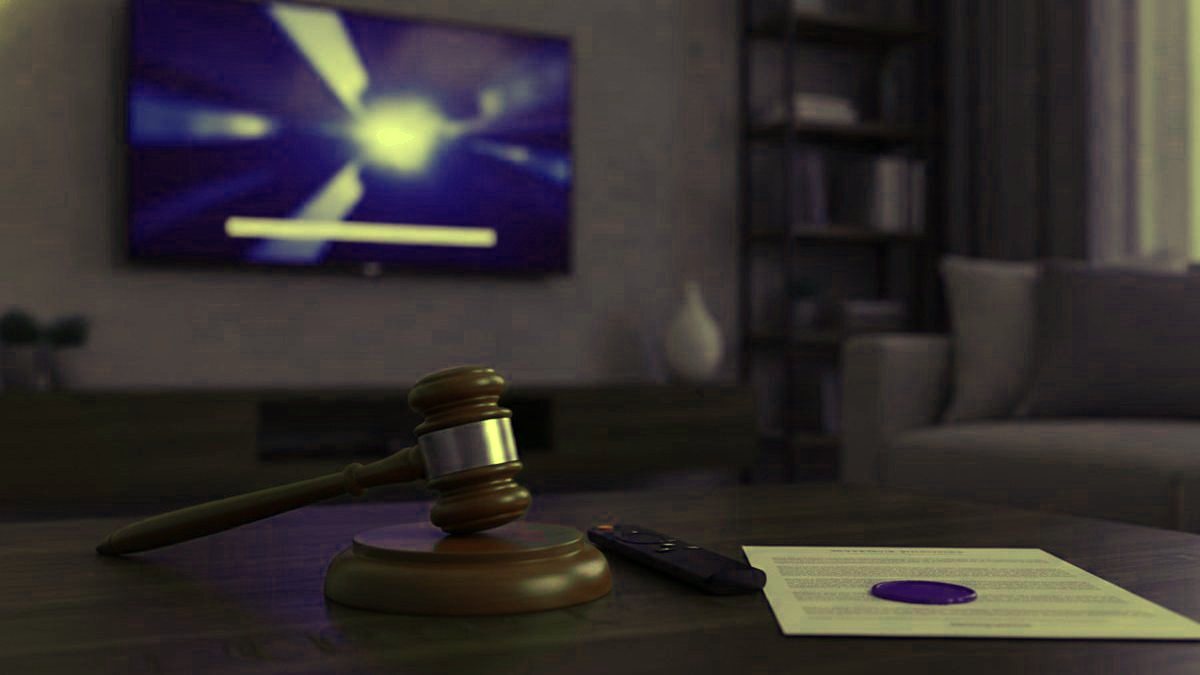 A gavel, a streaming remote and a sealed document on a coffee table in front of a TV